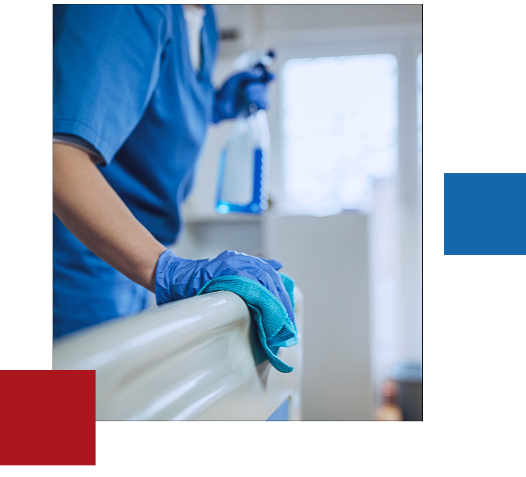 A woman is cleaning a hospital bed with a cloth and spray bottle.