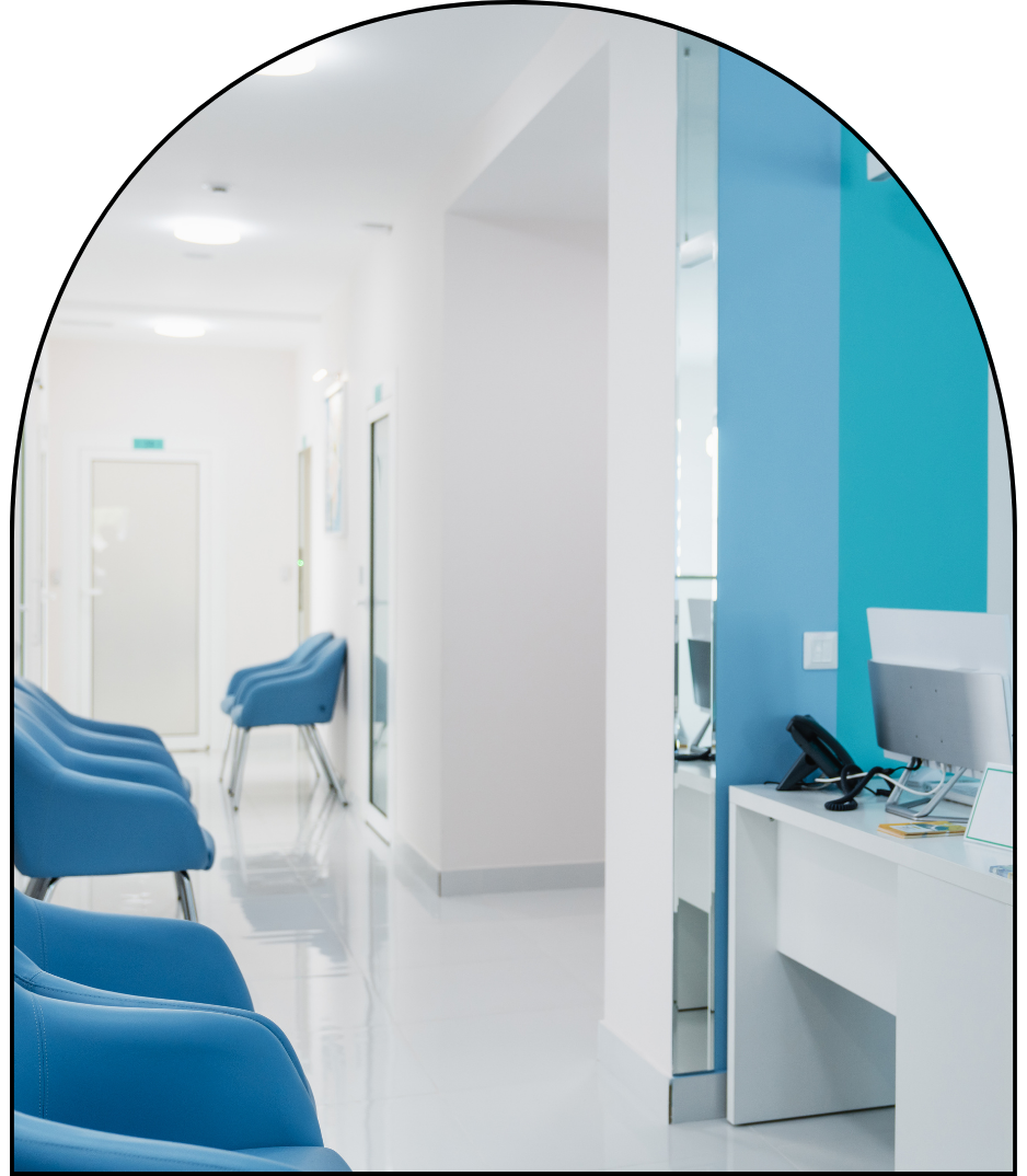 A hospital waiting room with blue chairs and a desk