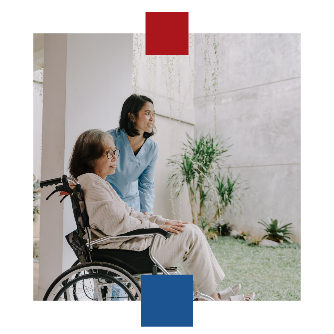 A woman is standing next to an older woman in a wheelchair.