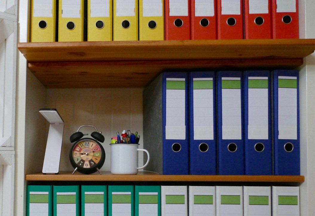 Organized office shelves with color coded folders