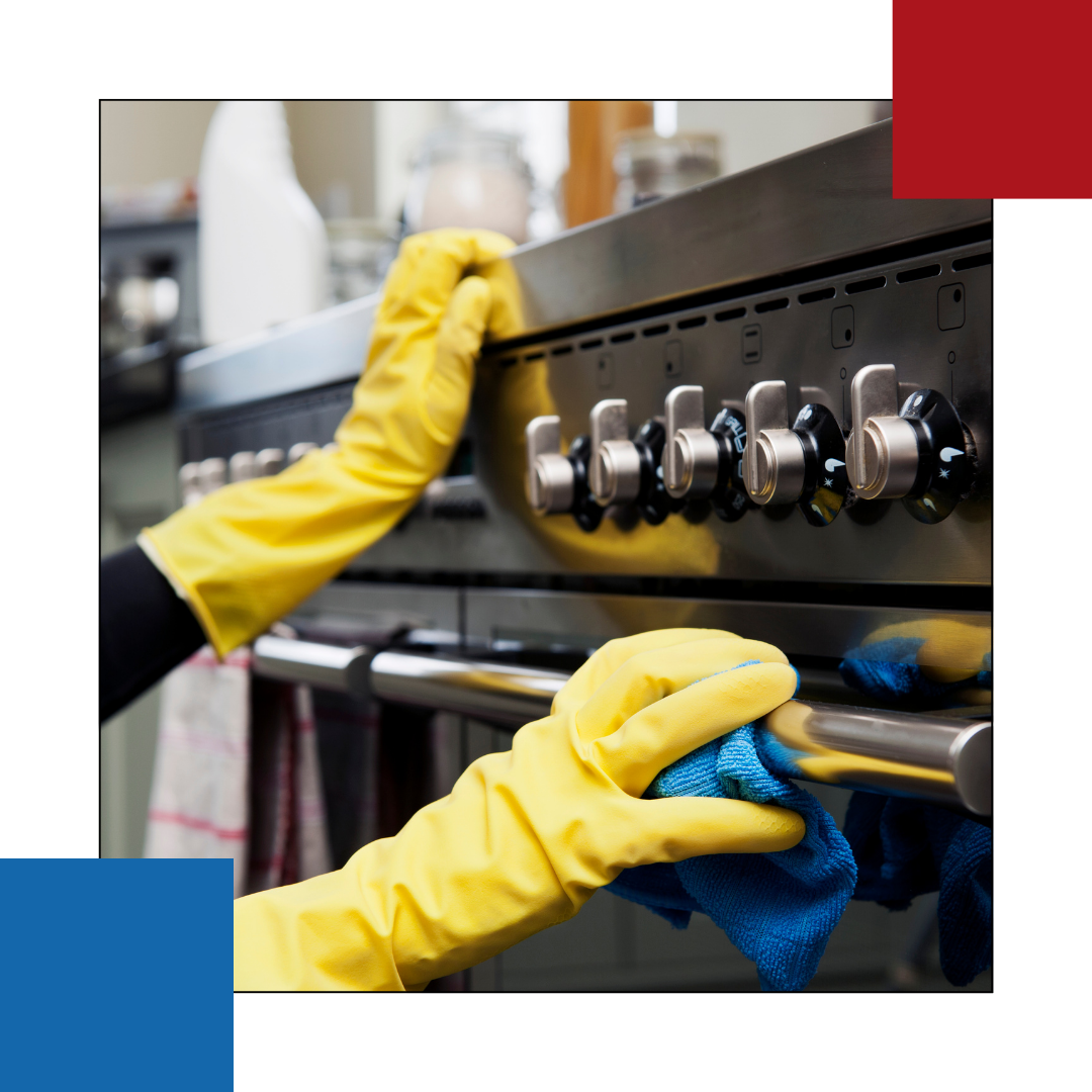 A person wearing yellow gloves is cleaning a stove