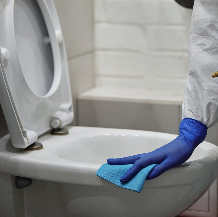 Professional cleaner disinfecting toilet in public bathroom
