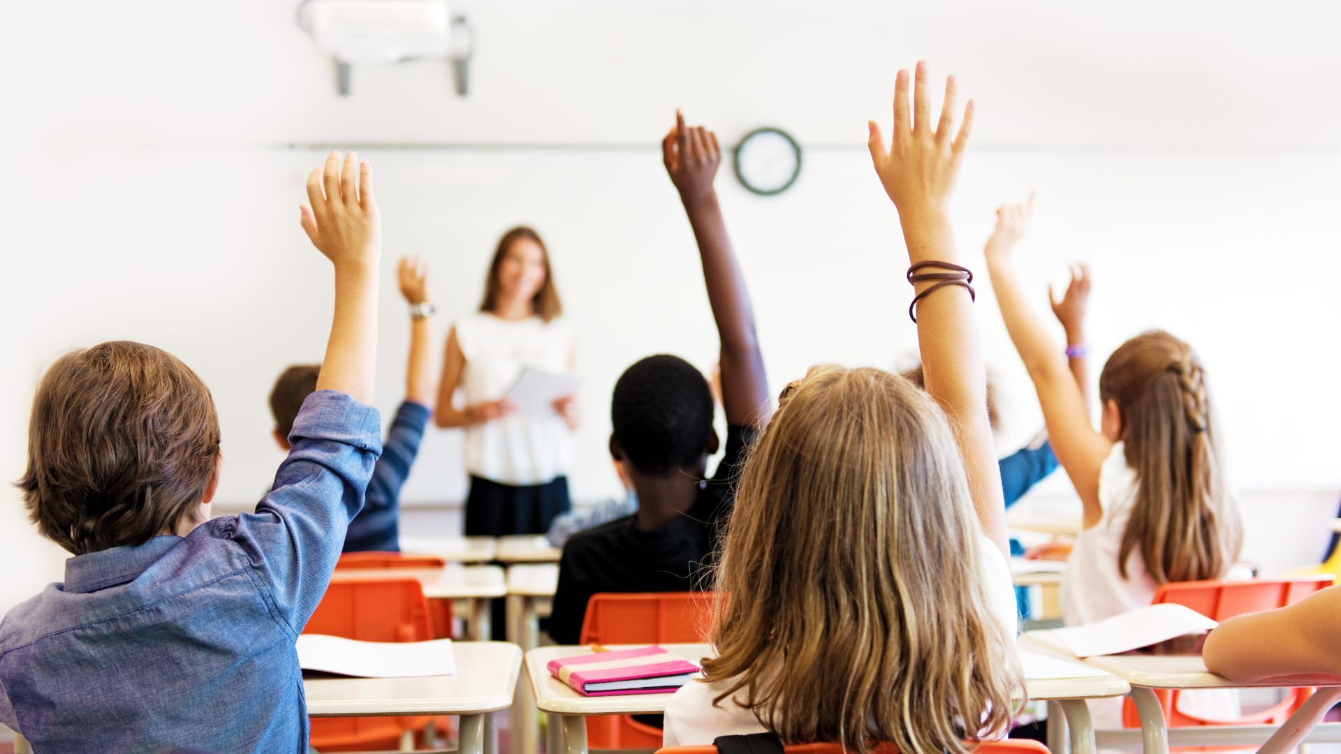 A classroom full of students with their hands raised.