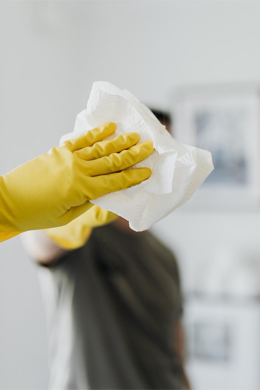 Professional Cleaner wearing gloves wiping mirror of public bathroom