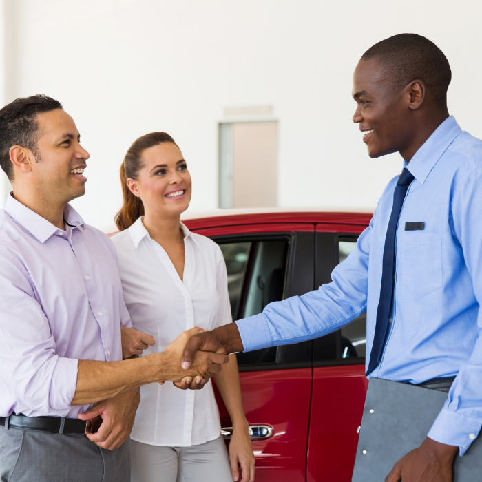 Salesman greeting customers at car dealership