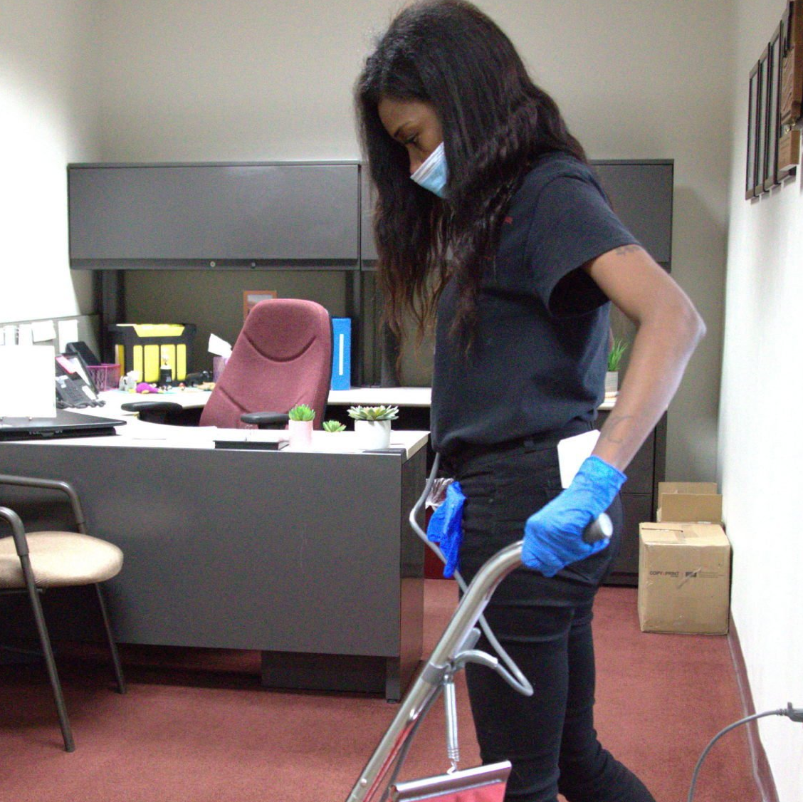 a woman wearing a mask and gloves is pushing a vacuum