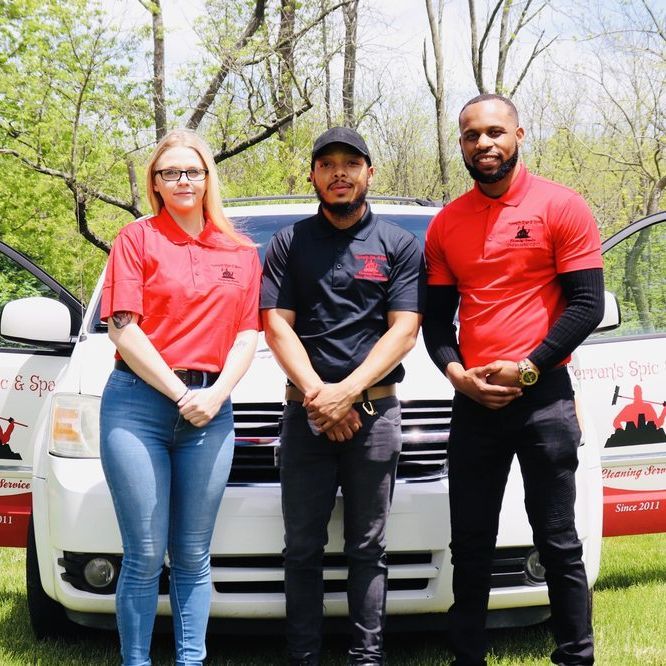 Terran's Spic & Span Cleaning team, wearing company uniforms, stand confidently in front of a company vehicle with the business logo outdoors on a sunny day
