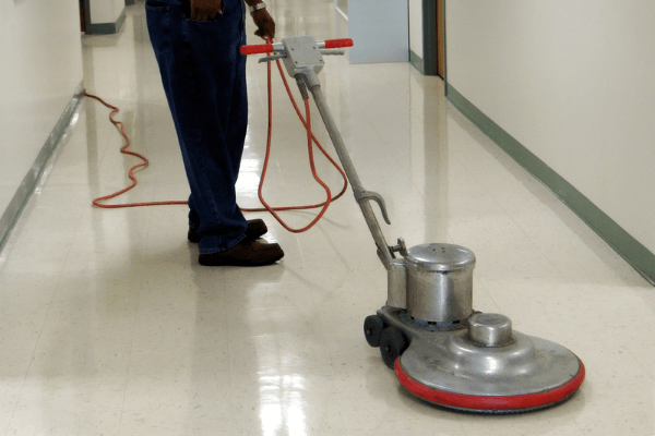 A commercial cleaner buffing an office hall floor