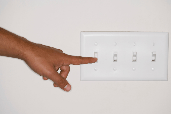 A hand pointing to a light switch for janitorial cleaning