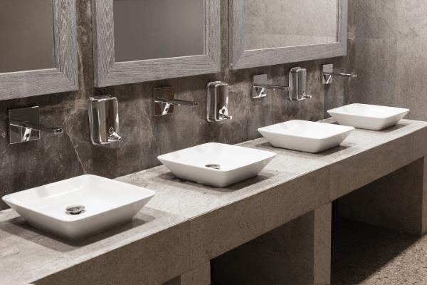 Four spotless restroom sinks, mirrors and soap dispensers for janitorial cleaning services