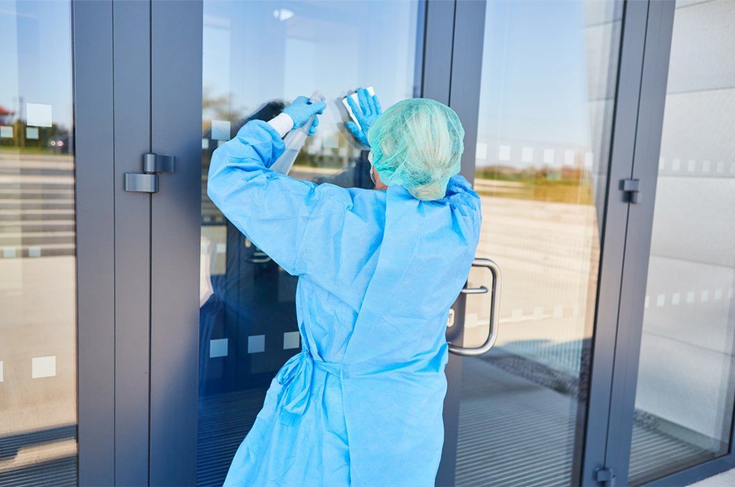 professional cleaner wiping window of medical office doors