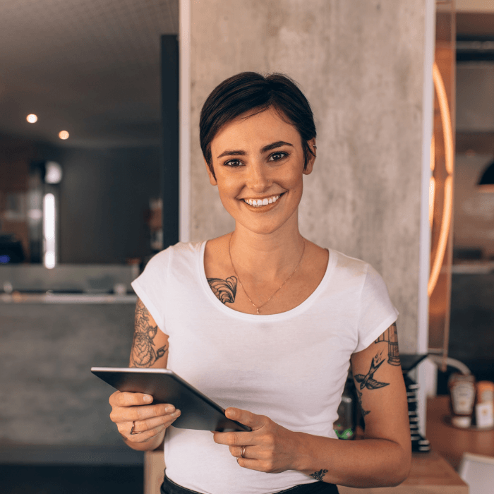 A smiling female restaurant owner welcoming diners in restaurant dining room