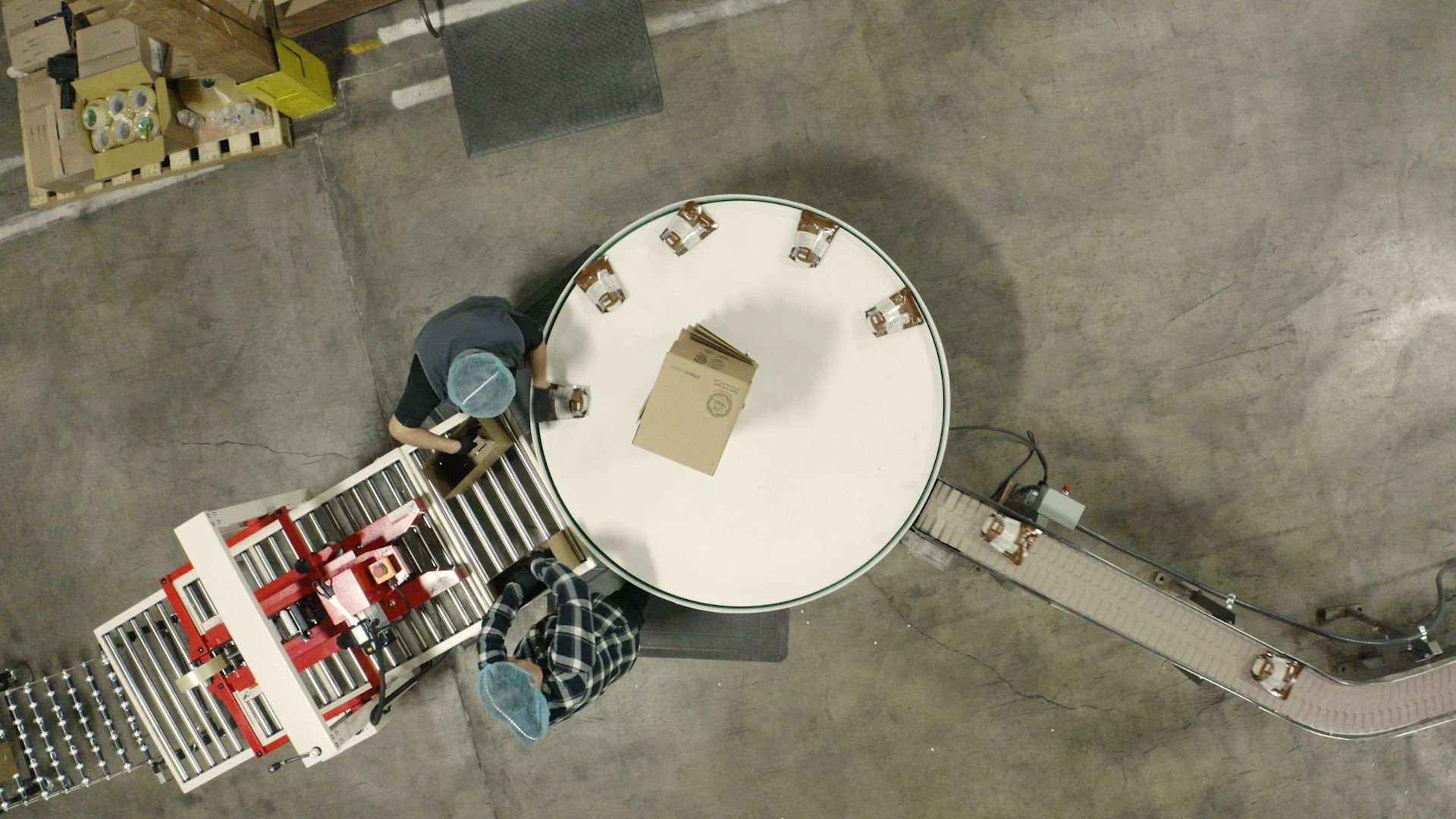Two employees packaging food on the food processing line.