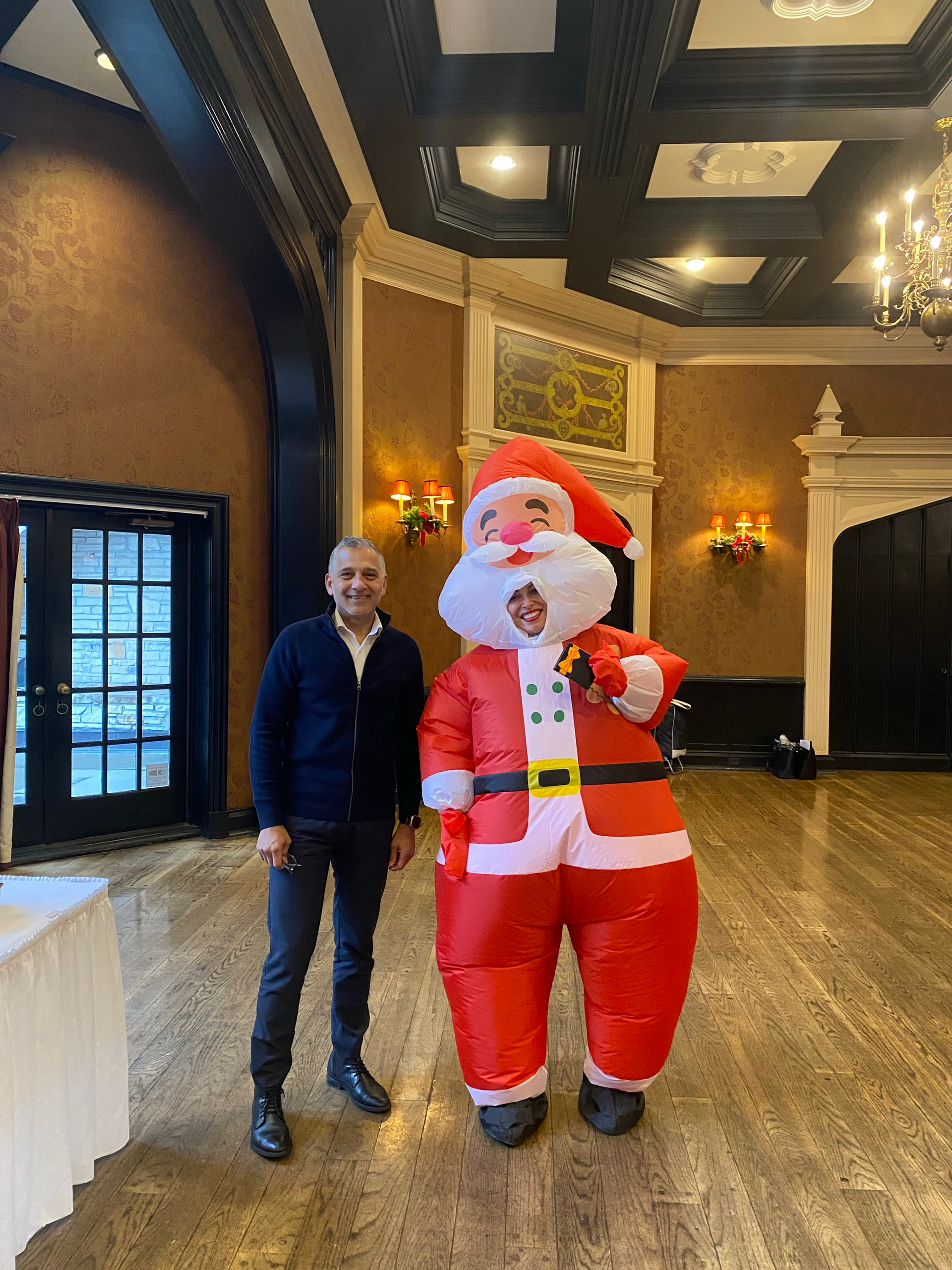 A man is standing next to an inflatable santa claus in a room.