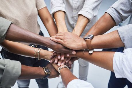 A group of people are putting their hands together in a circle.