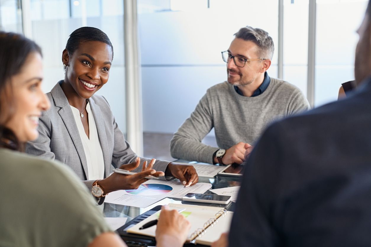 A group of people are sitting around a table having a meeting.