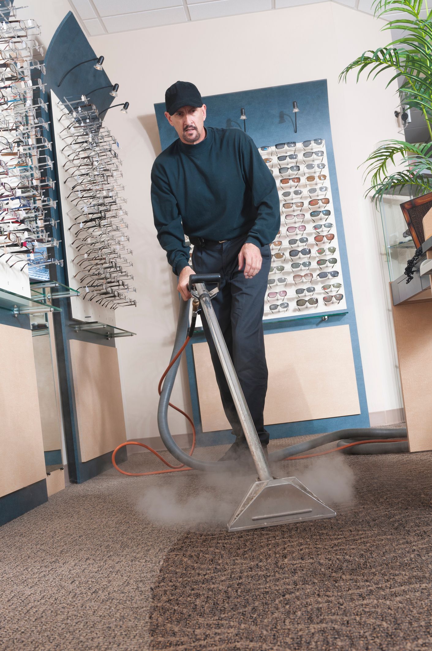Person vacuuming a blue patterned carpet with a black and silver vacuum cleaner.