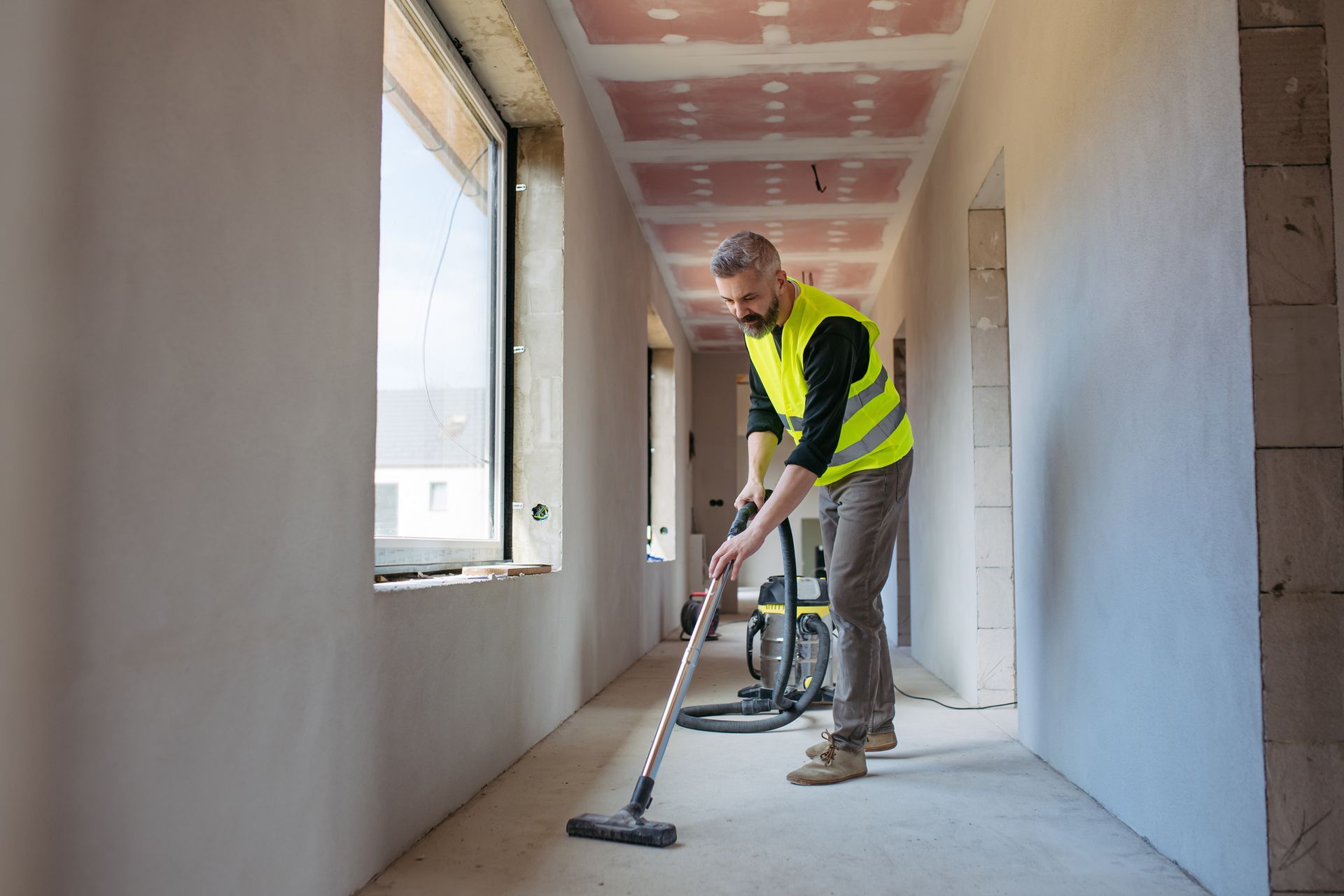 Bags of trash and a stack of wooden crates inside a building with large glass windows.