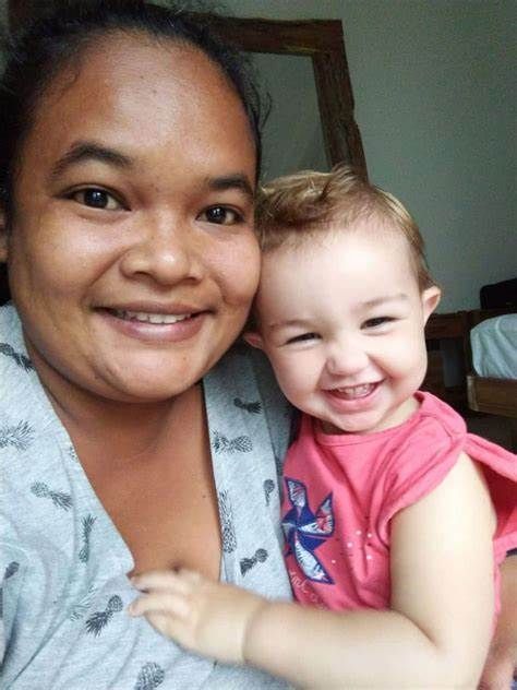 A woman is holding a baby in her arms and smiling.