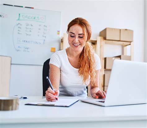 A woman is sitting at a desk in front of a laptop computer.