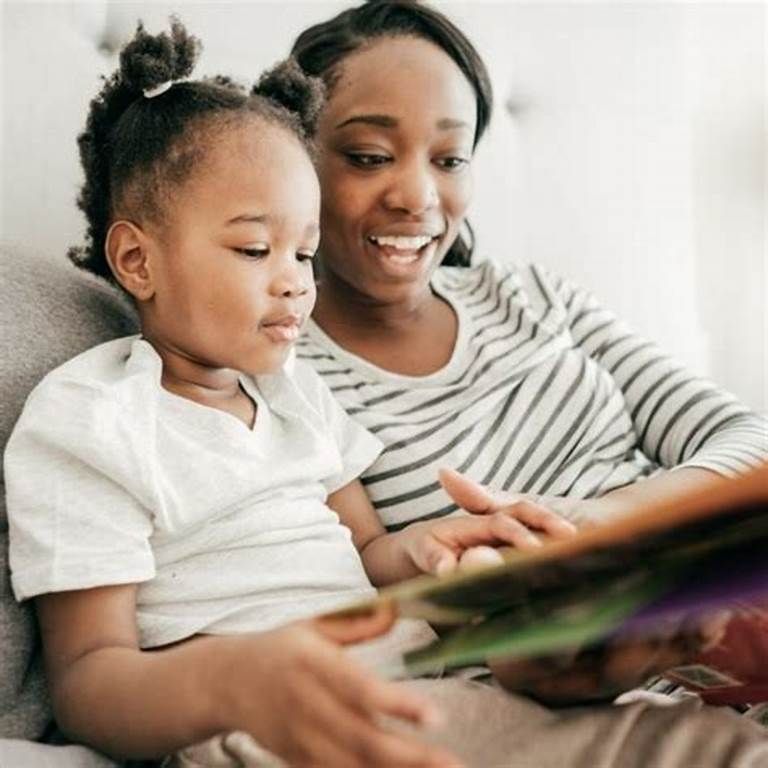 A woman is reading a book to a little girl on a couch.