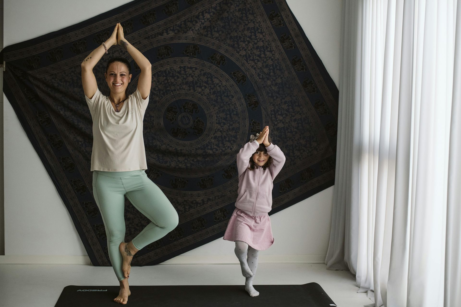 A woman and a little girl are doing yoga together.