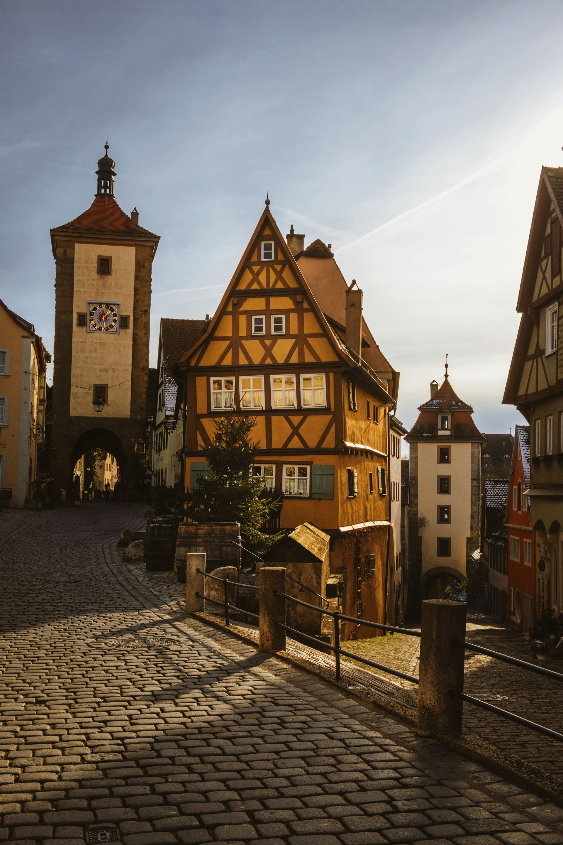 A cobblestone street with a clock tower in the background