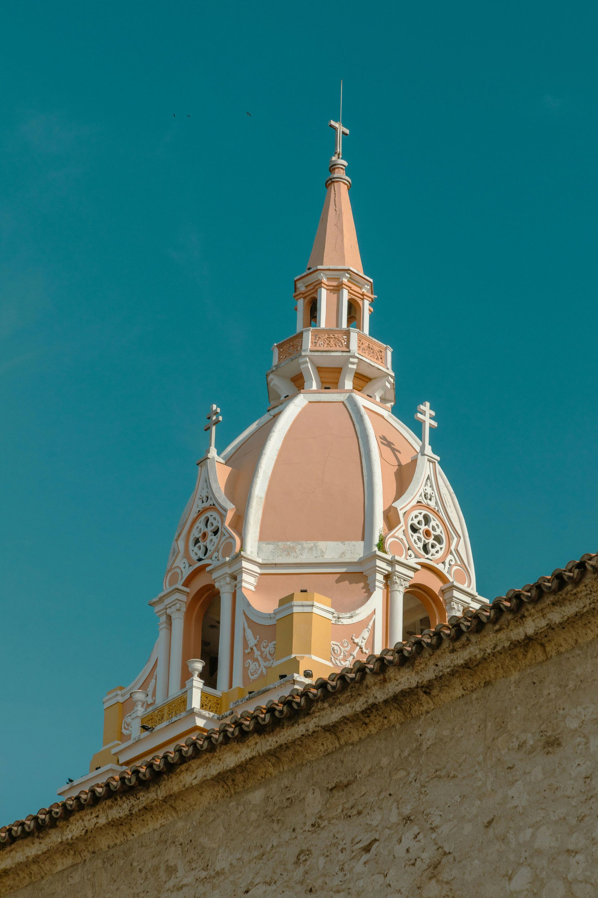 A pink and white dome with a cross on top of it is on the roof of a building.