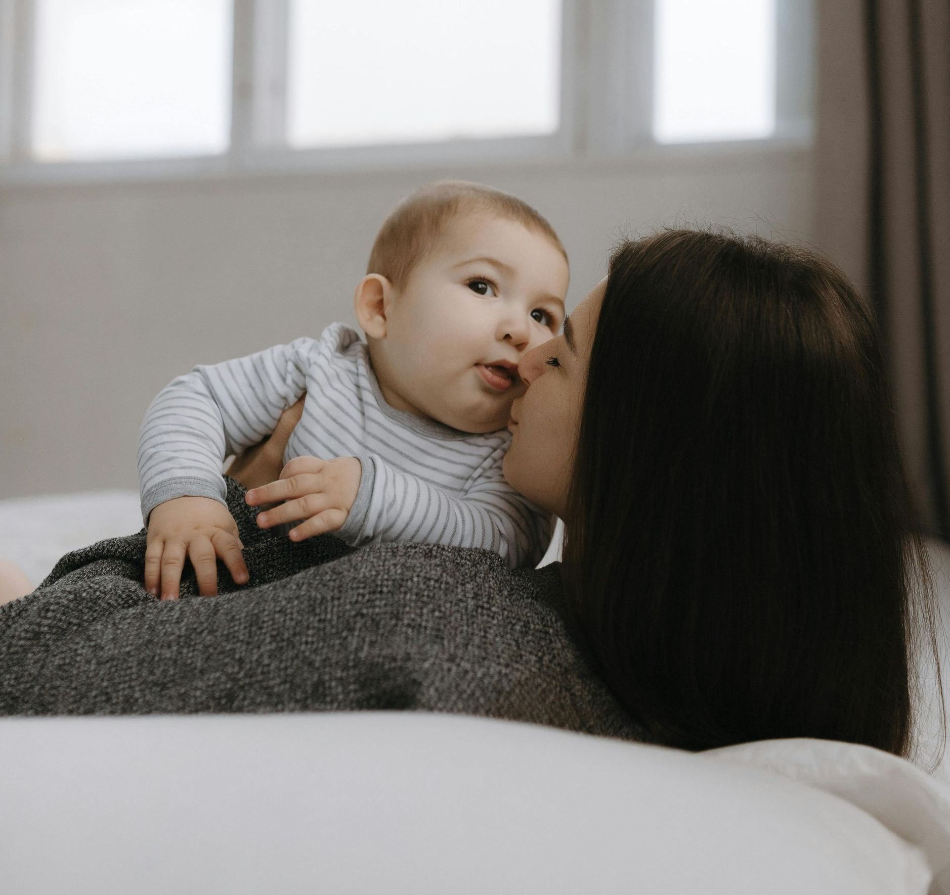 A woman is holding a baby in her arms and kissing it on the cheek.