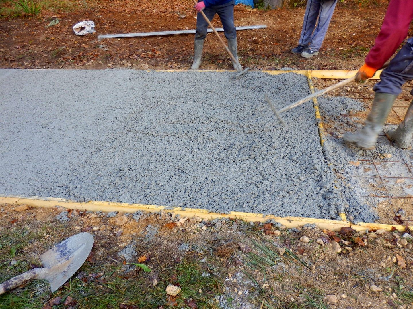 A group of people are working on a concrete driveway.