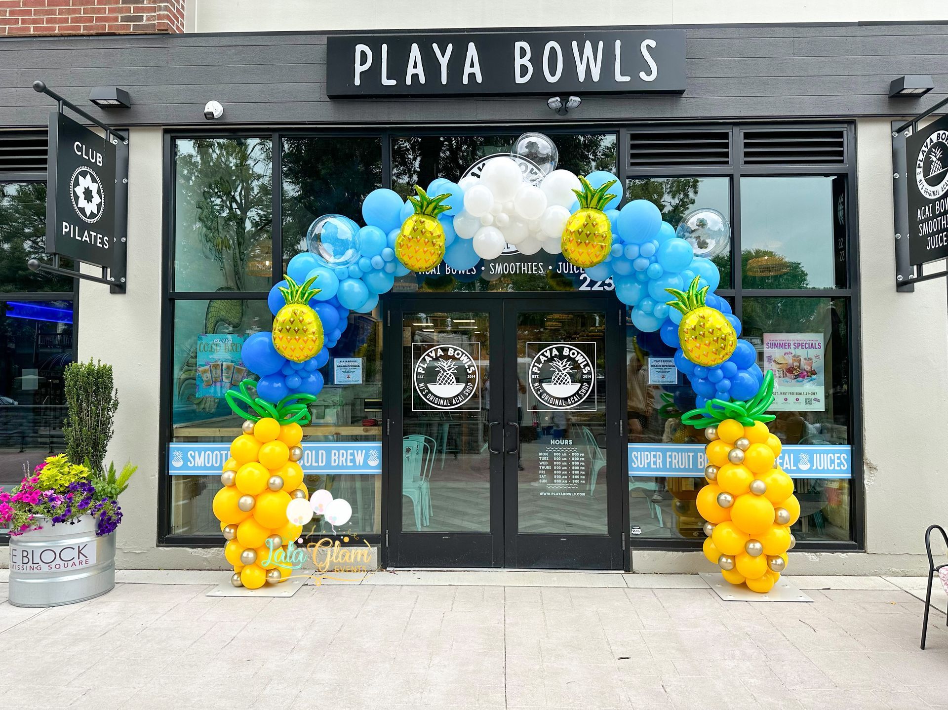 Exterior of Playa Bowls storefront with balloon arch in blue and yellow.