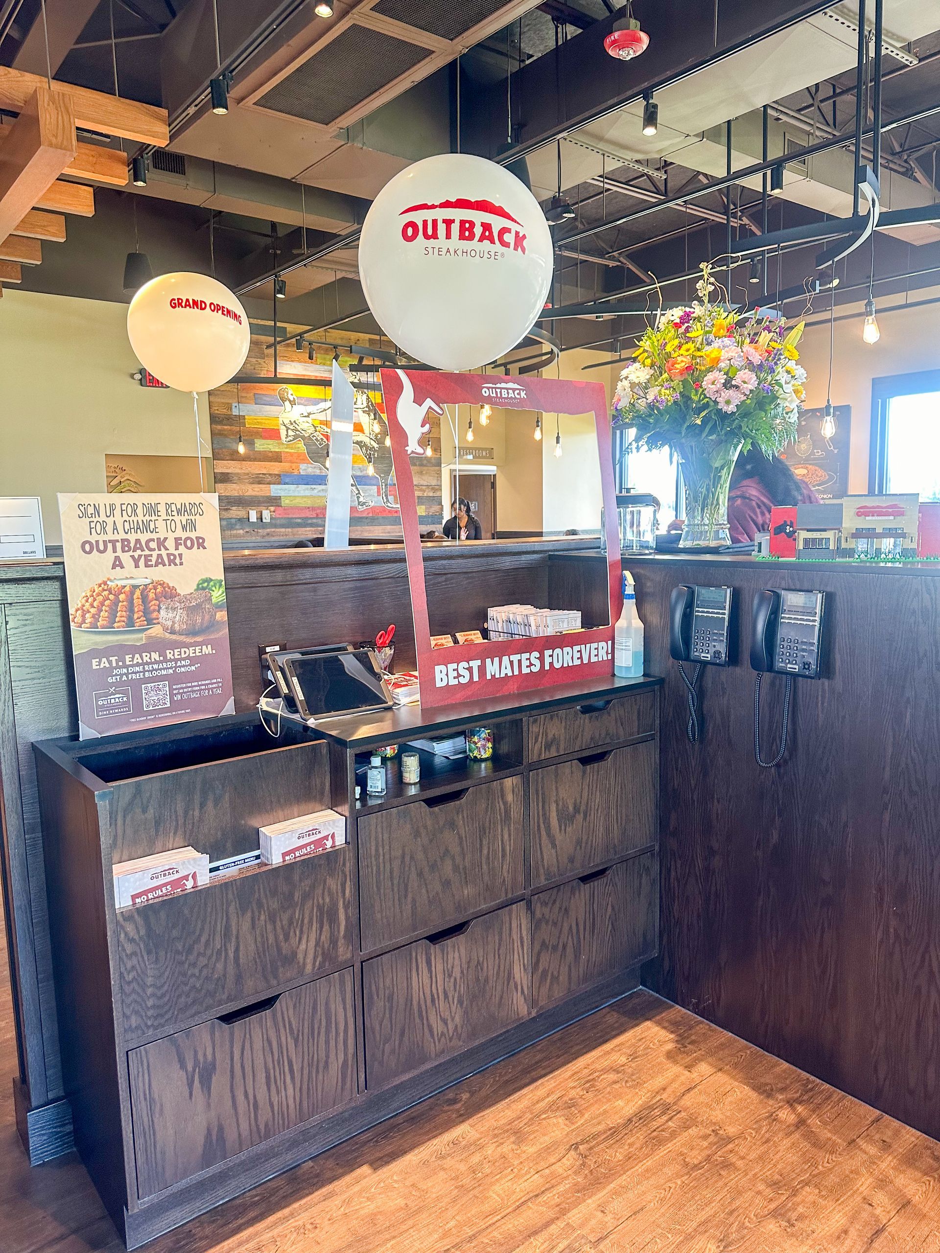 Outback restaurant entrance with balloons, checkout counter, and brochures.