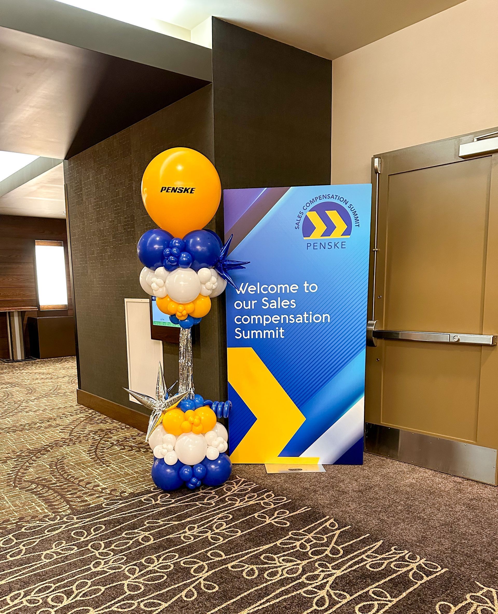 A welcome sign and balloon display for a sales compensation summit.