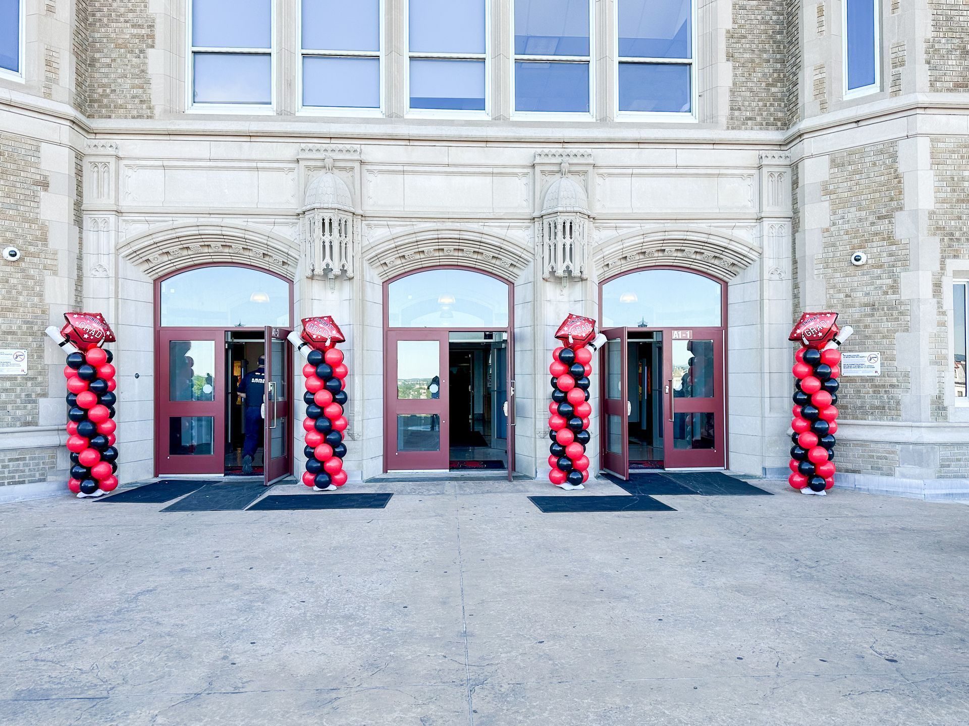 Entrance to a building with red and black balloon columns flanking open doors.