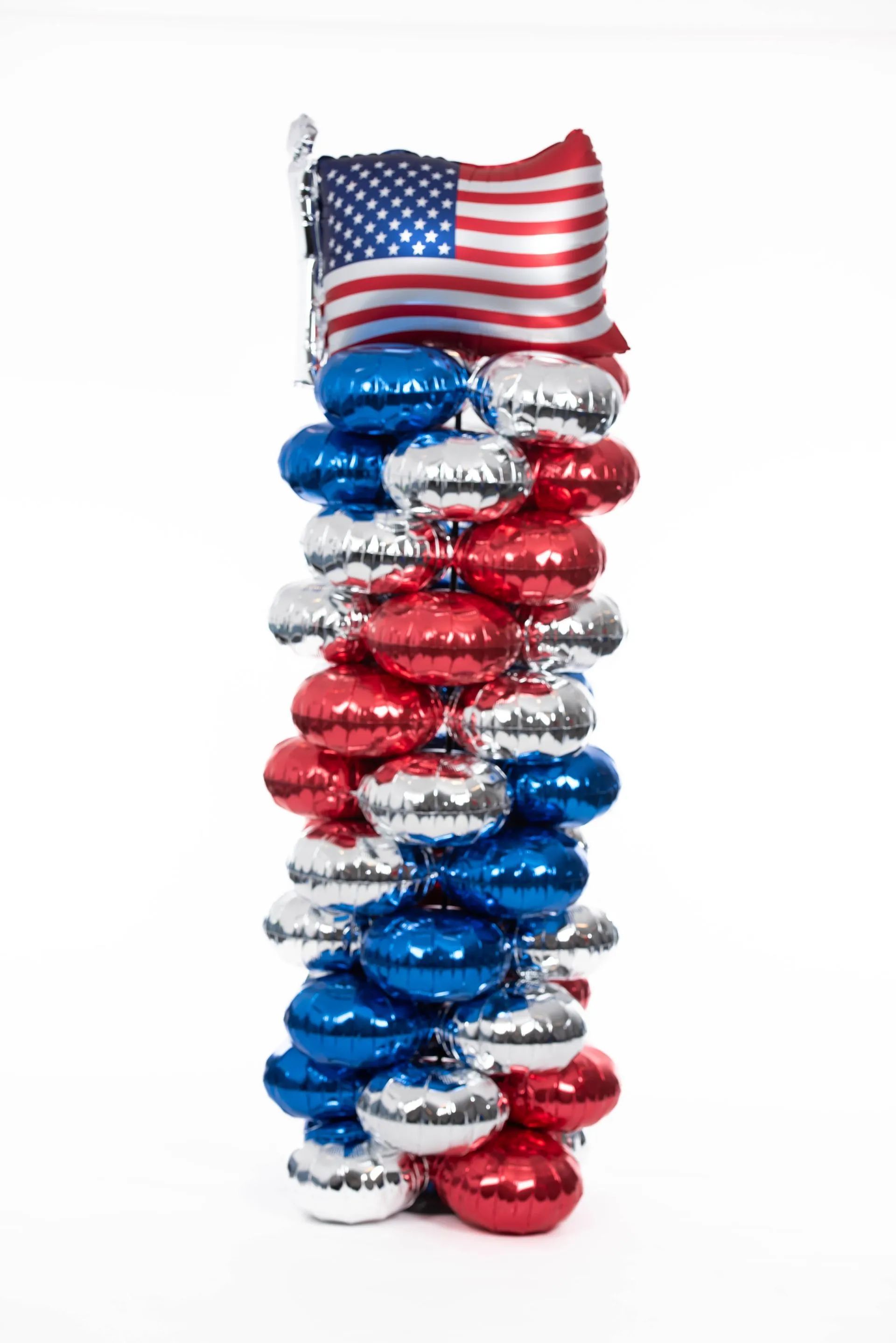 Red, white, and blue balloon column with American flag topper; patriotic decoration.