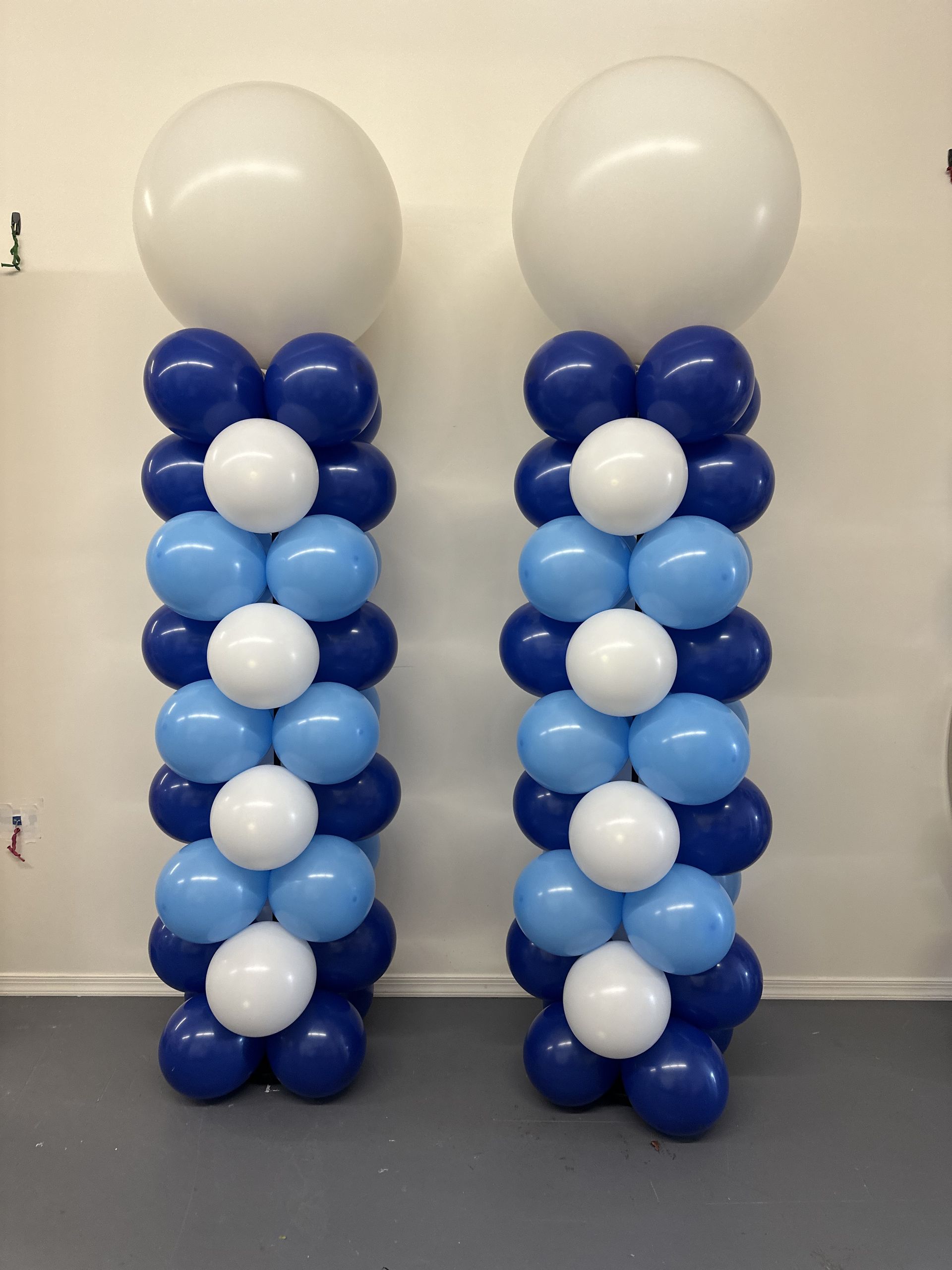 Two blue and white balloon columns topped with large white balloons.