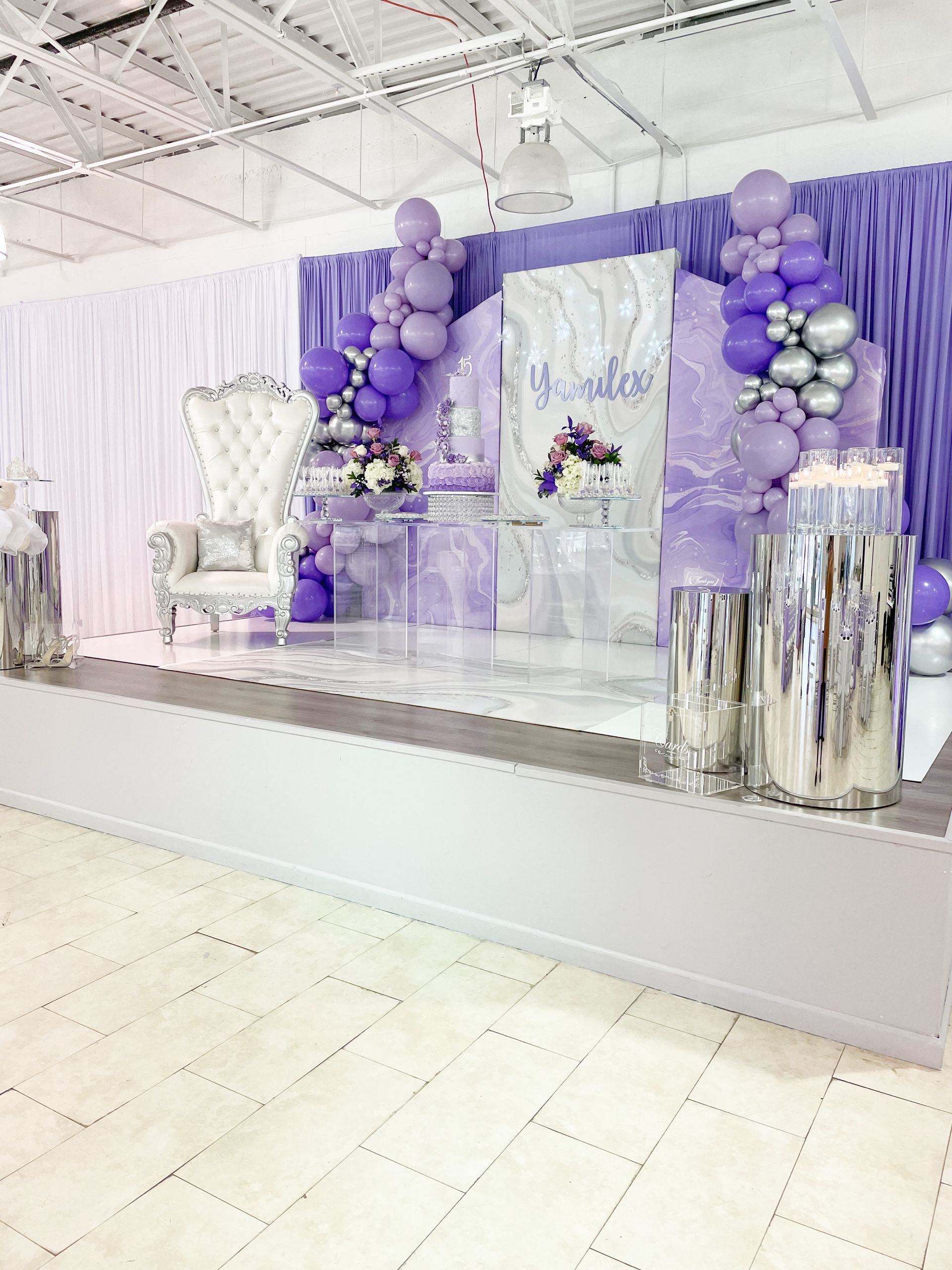 Purple-themed event stage with balloons, a throne chair, and silver accents.