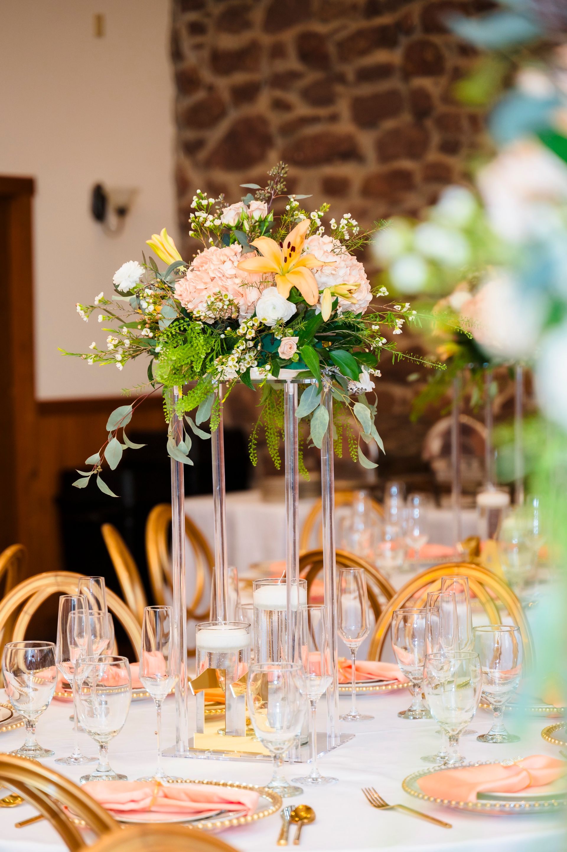 Elegant floral centerpiece on a table set for a formal event. Peach and white flowers with gold accents.