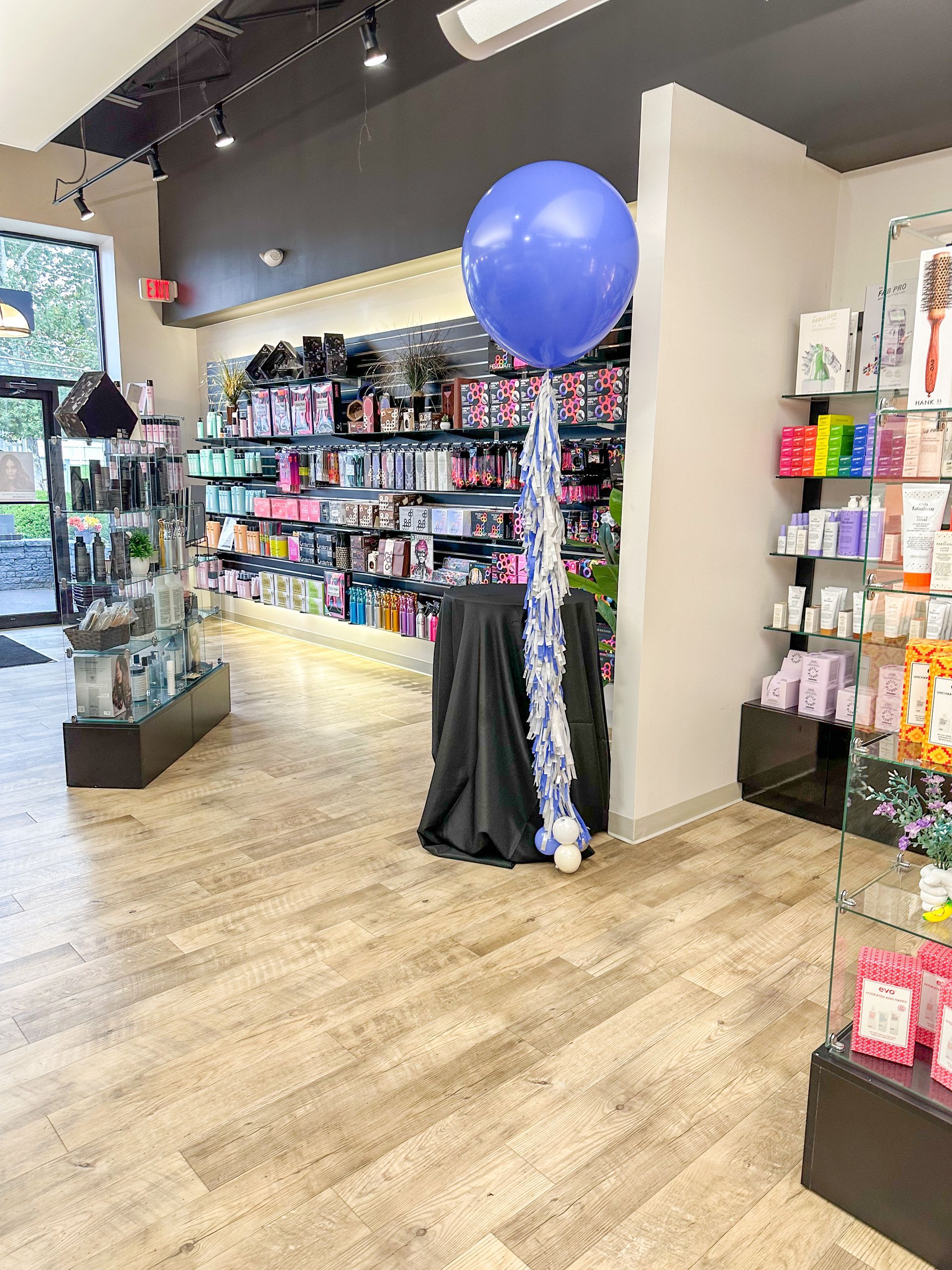 Interior of a beauty supply store with a large blue balloon and product displays.