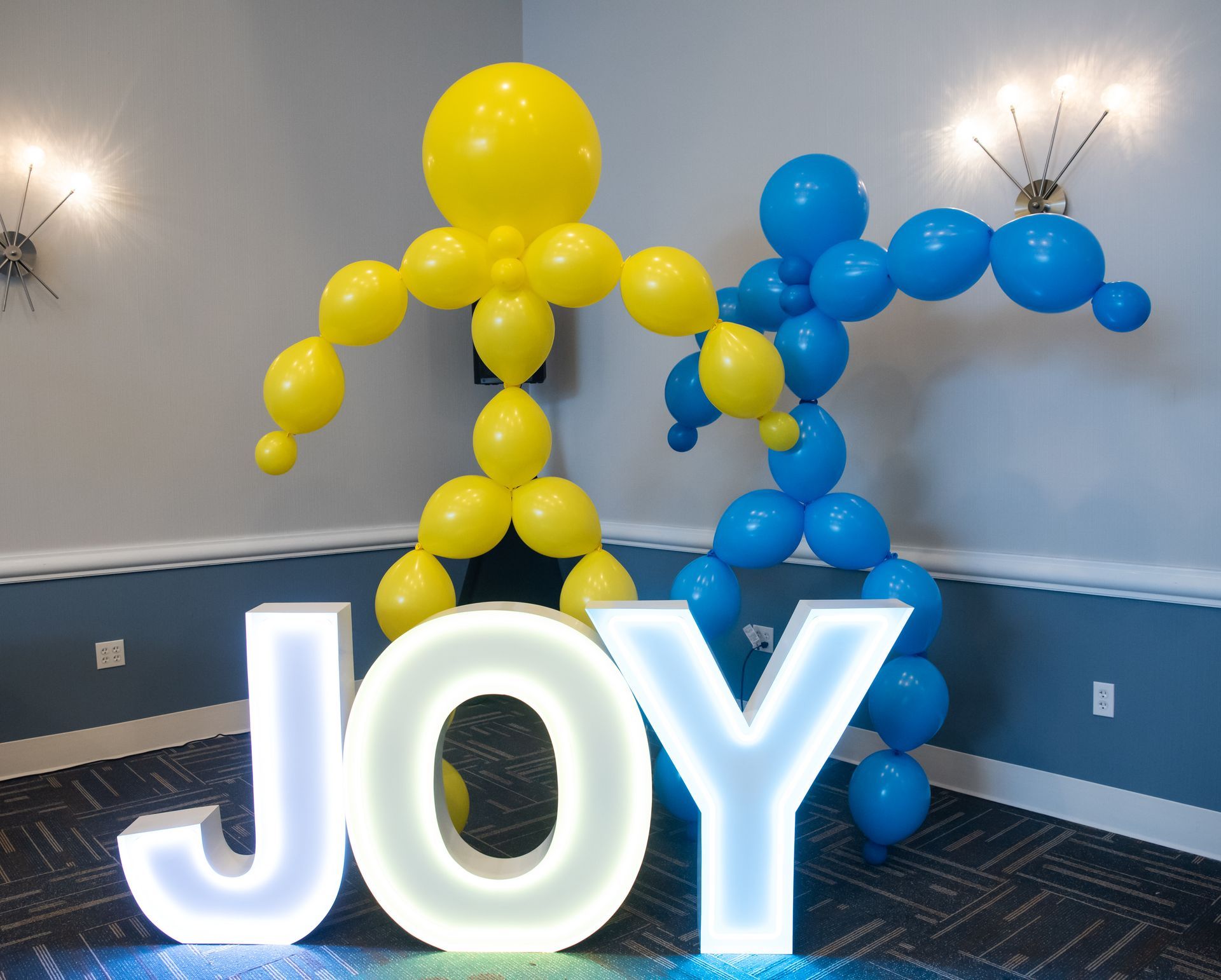 Yellow and blue balloon figures flanking a lit-up