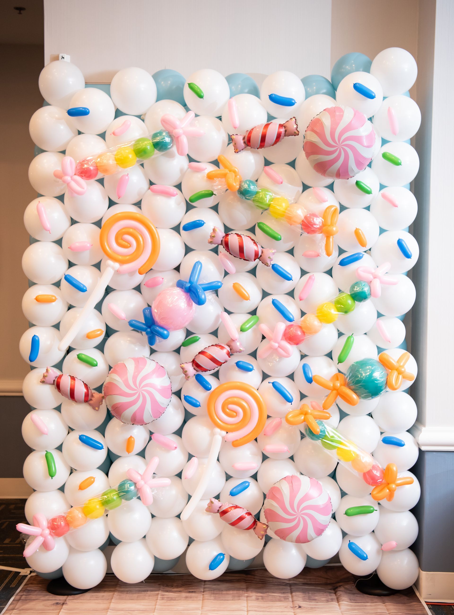 Balloon wall decorated with white and blue balloons, candy-shaped balloon creations.
