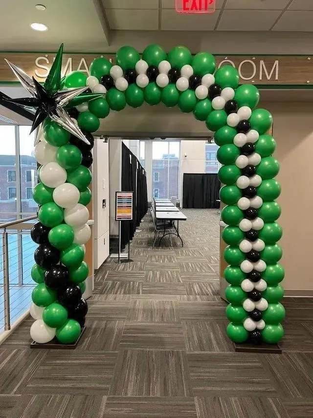Balloon arch in green, black, and white over a doorway. A star decoration is on the left.