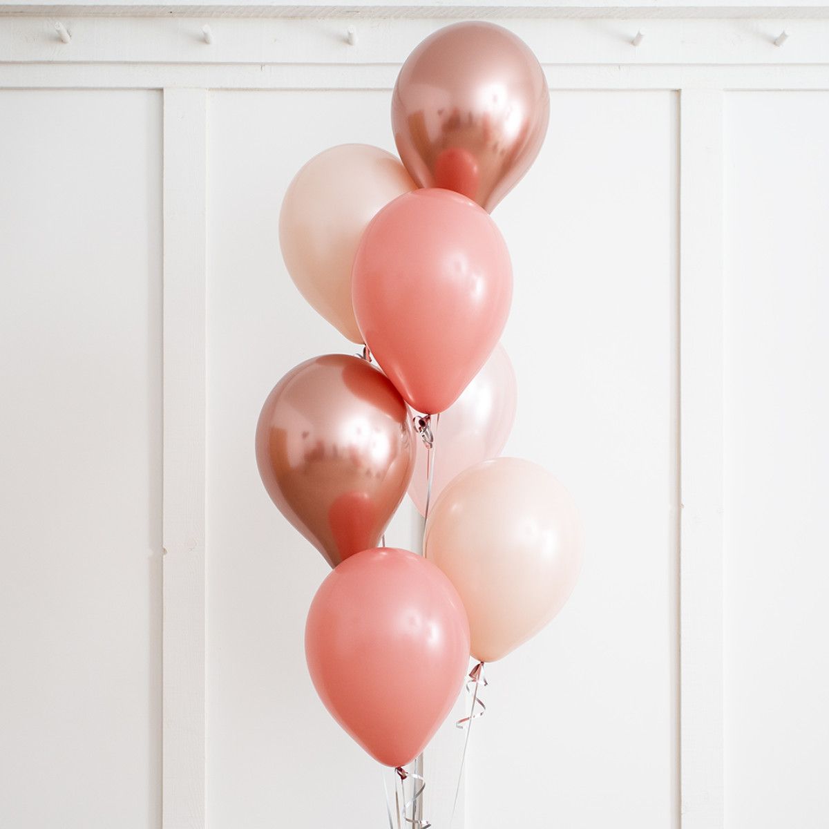 Bouquet of pink and rose-gold balloons against a white background.