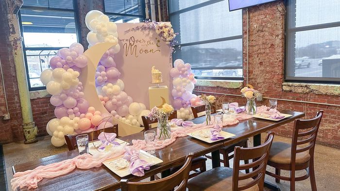 Baby Shower party backdrop: balloon arch in purple and colors with a cake on a pedestal.