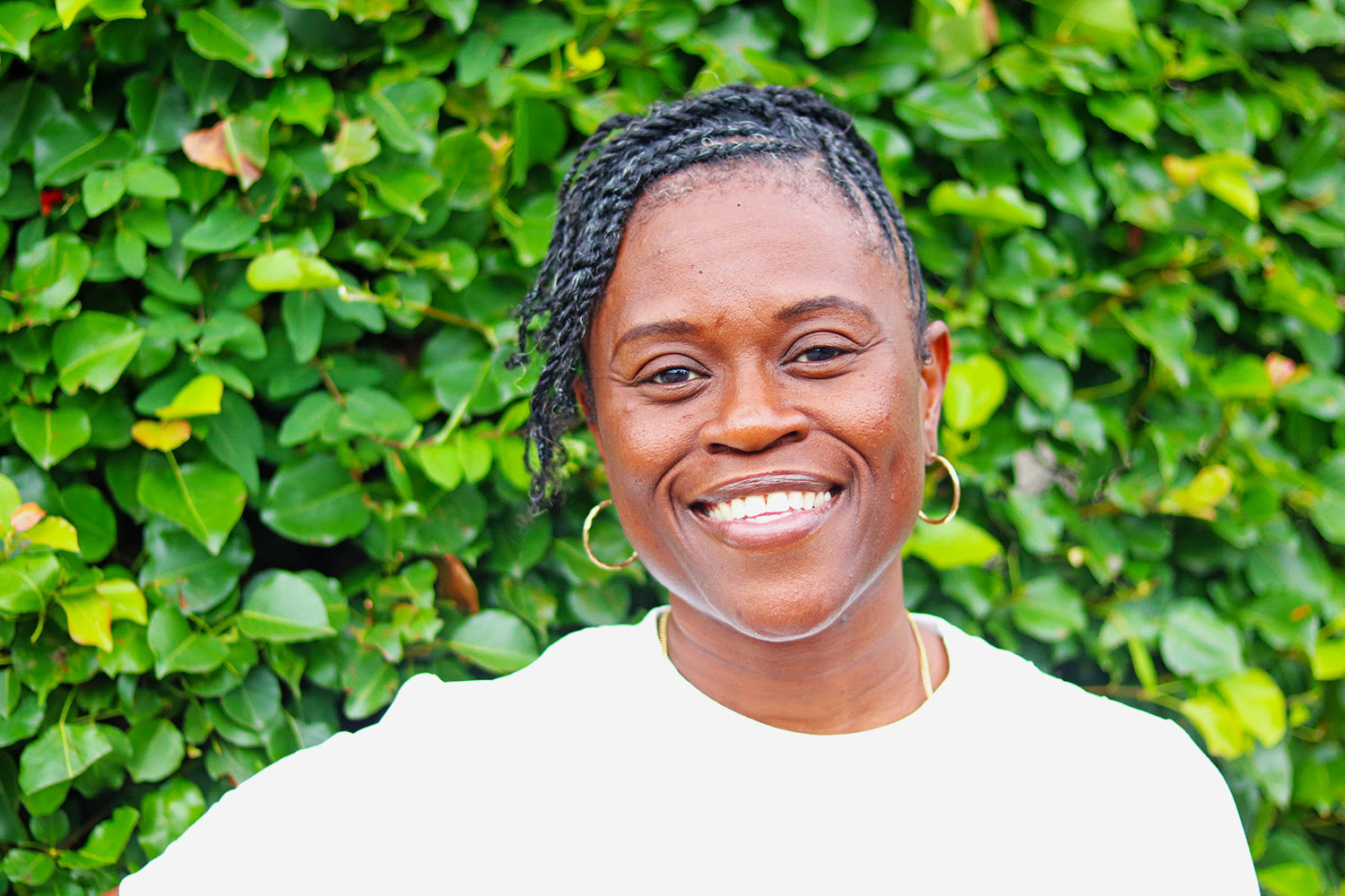 A woman is sitting on a couch talking to another woman while holding a laptop.