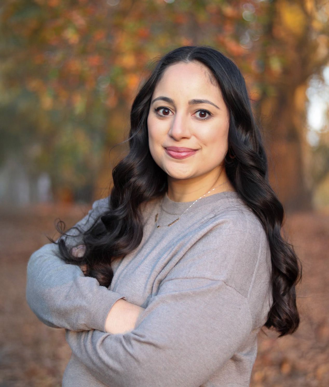 A woman with long dark hair is smiling for the camera.