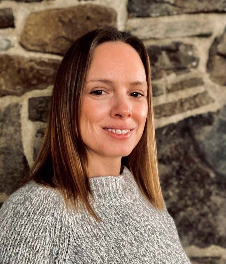 A woman is writing on a clipboard while a man wearing a mask looks on.