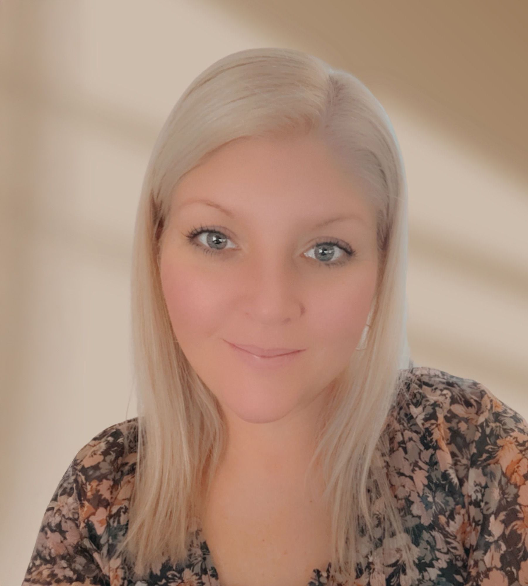 A woman is sitting on a couch talking to another woman while holding a laptop.