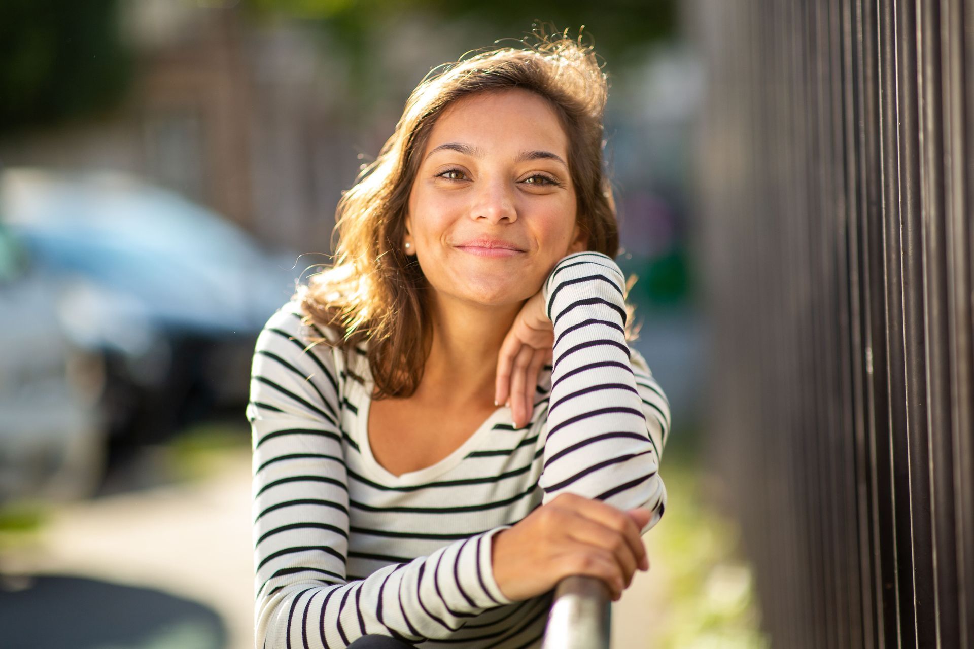 A woman is sitting on a couch with her hands folded and smiling.