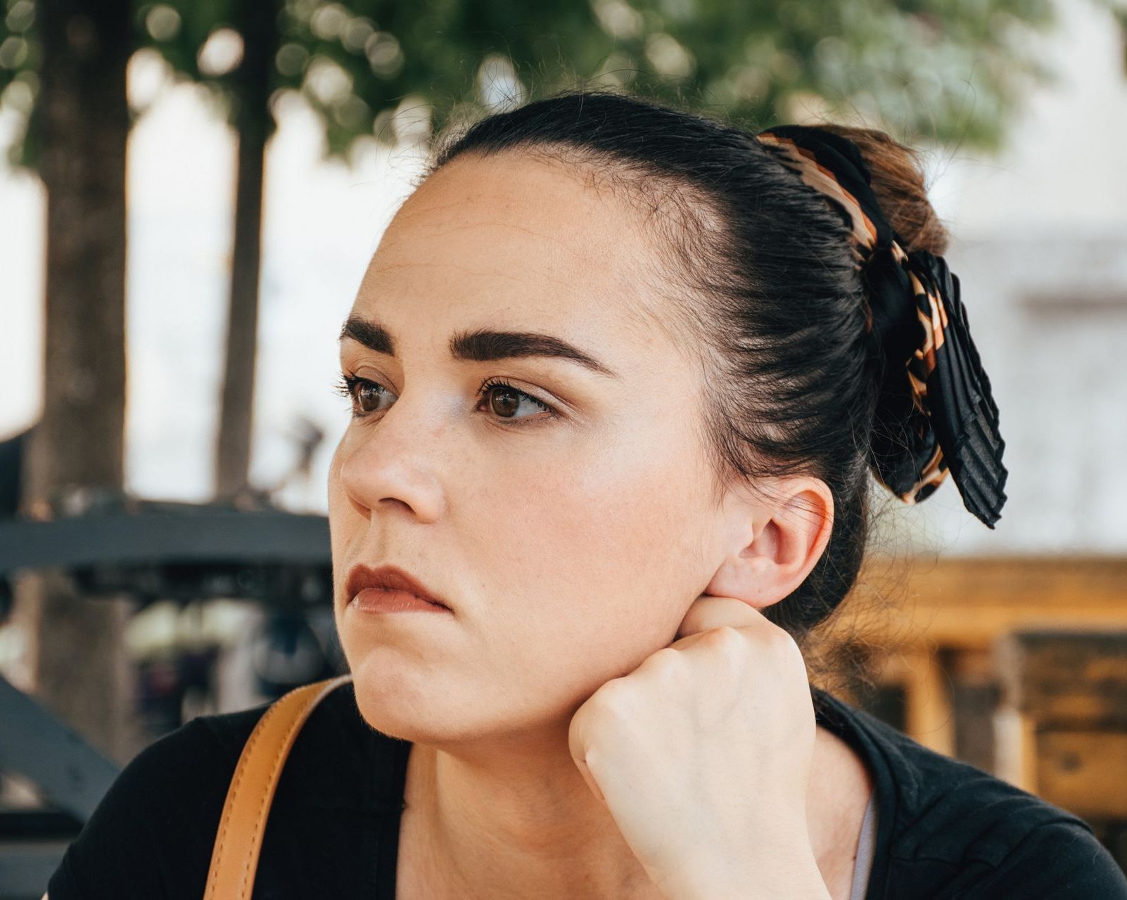 A woman is sitting at a table with her hand on her chin.